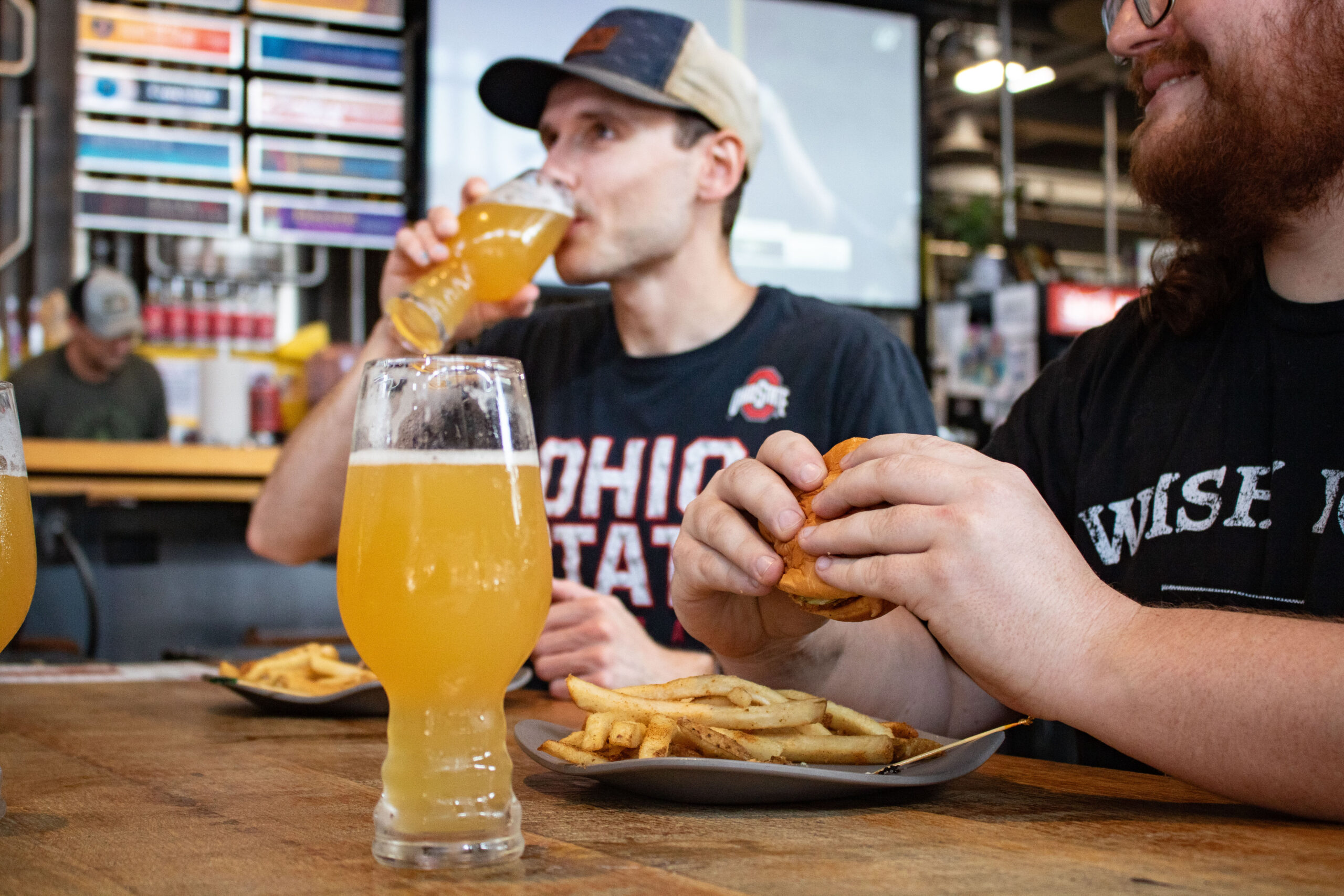 Two guys hanging out enjoying a beer and a burger.