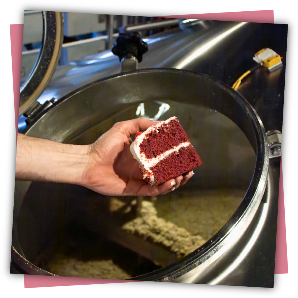 A brewer throwing a chunk of cake in the mash tun.