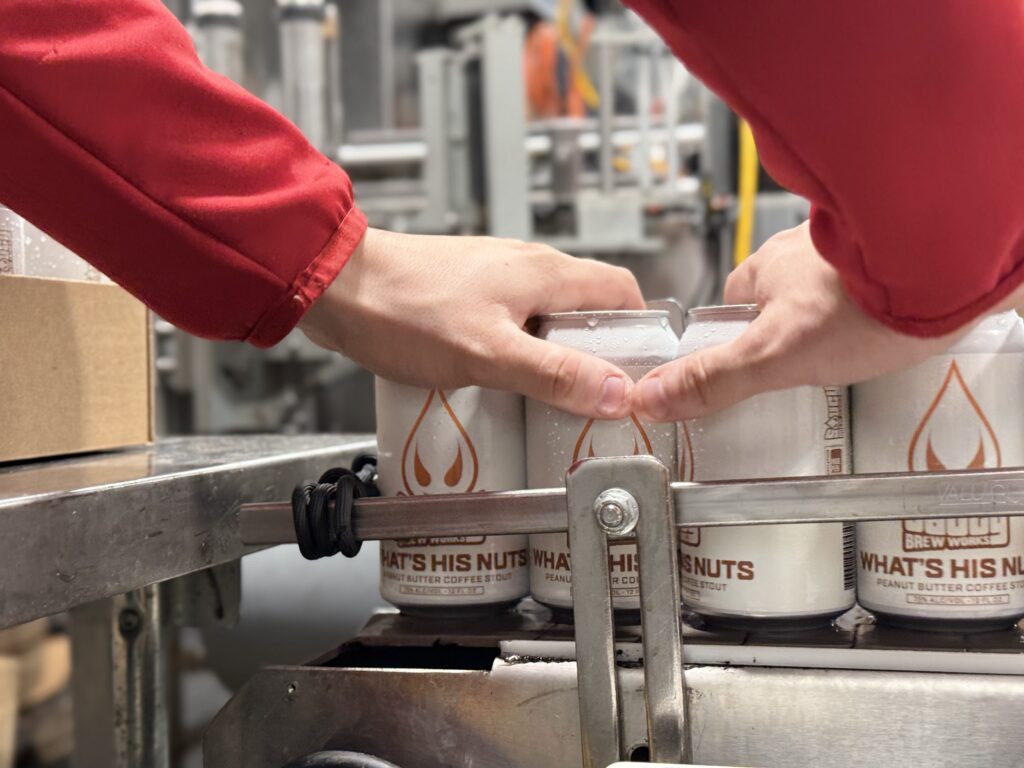 hands picking up What's His Nuts cans off the canning line.