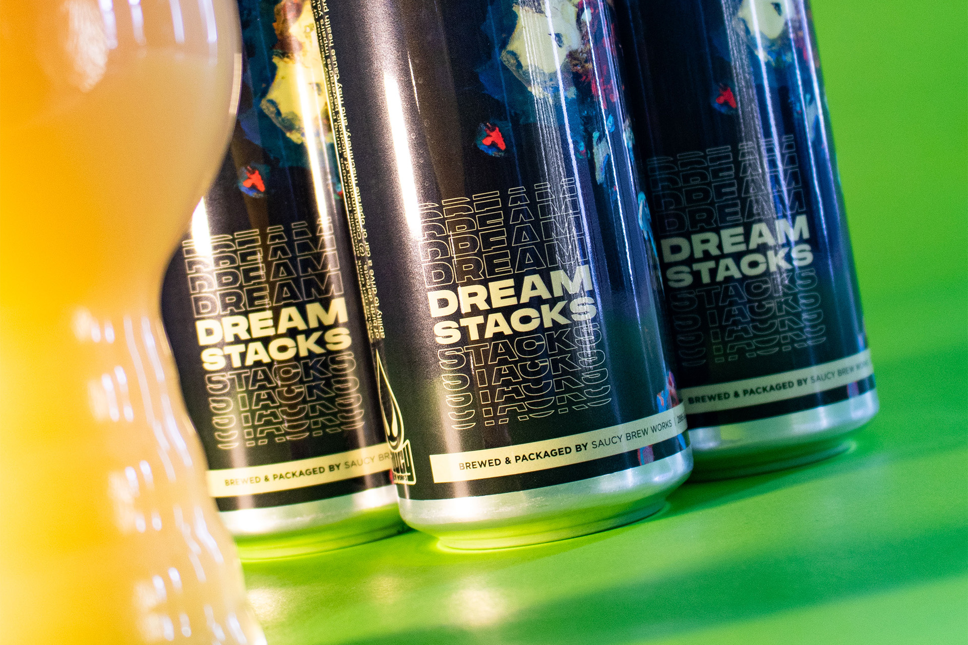 Cans of Dreamstacks on a lime green background with a draft beer.